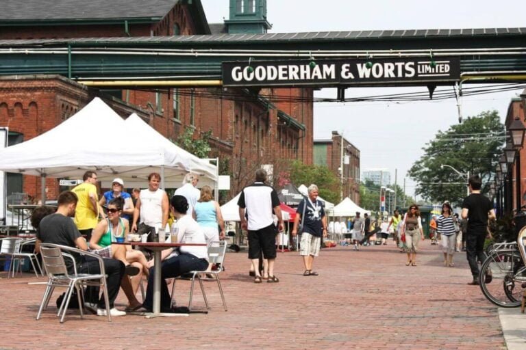 A vibrant scene in Toronto's Distillery District, showcasing Victorian-era architecture, bustling with shoppers and diners.