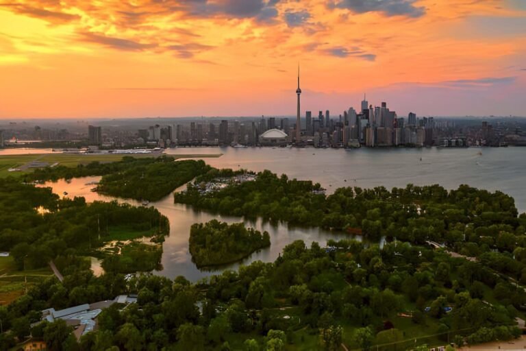 A serene view of the Toronto Islands showing sandy beaches, green parks, and the amusement park against the city skyline.