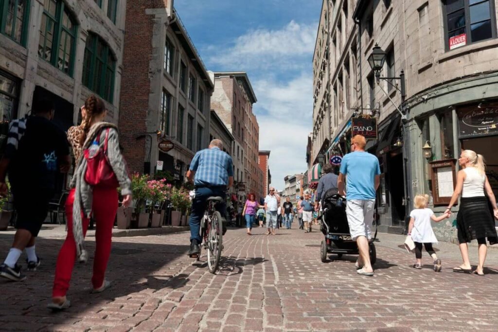 Narrow cobblestone streets lined with historic buildings, bustling with shoppers and café-goers in Old Montreal.
